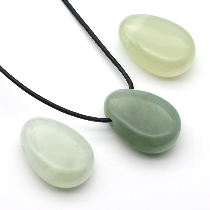 Drei grüne Serpentin-Anhänger (China-Jade) in unterschiedlichen Naturtönen, einer mit schwarzem Lederband auf weißem  Hintergrund.